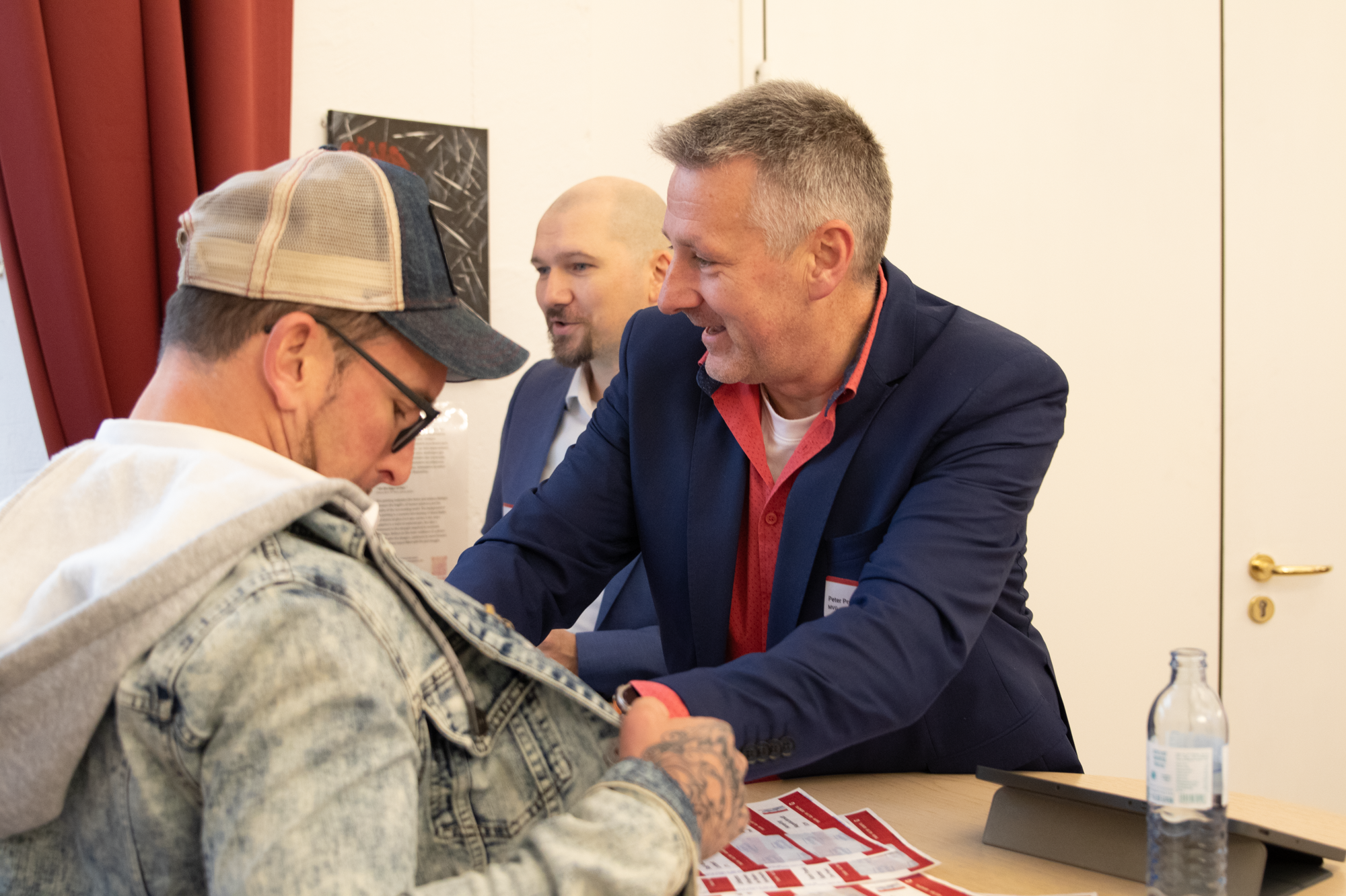 Zwei MVG Mitarbeiter verteilen Namensschilder an einem Trafikanten