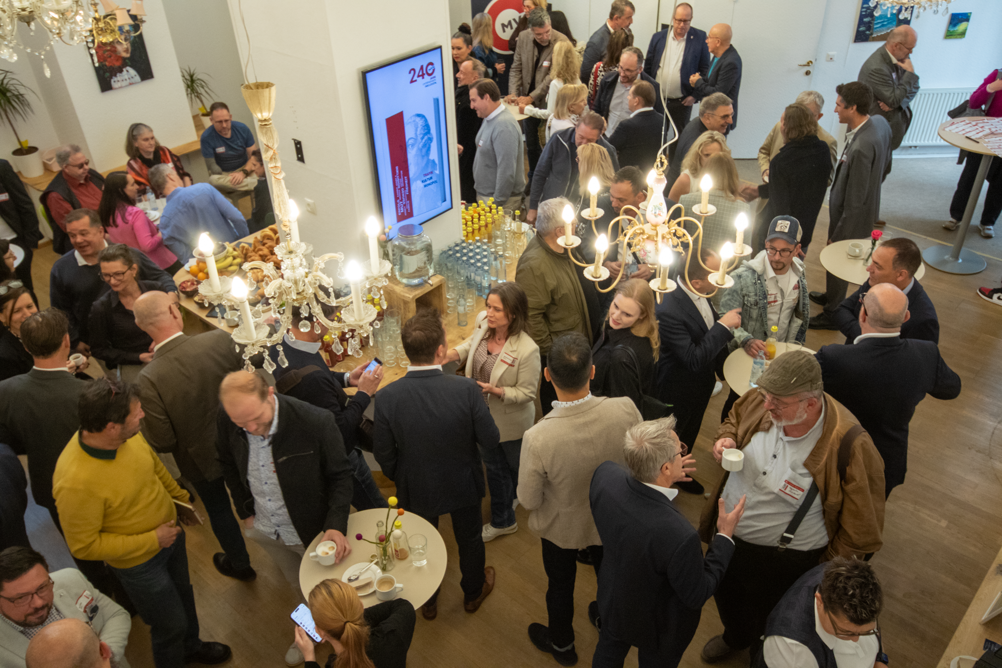 Perspektive von oben, eine Gruppe von Besuchern versammeln sich in einem Raum und warten bis die Veranstaltung anfängt