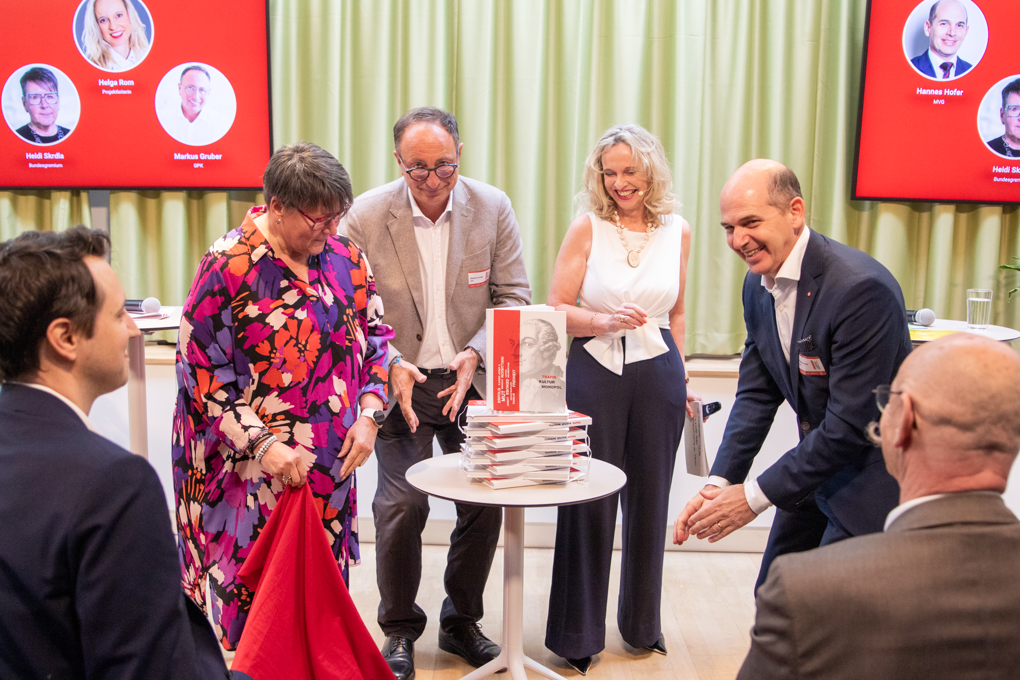 Vier Personen stehen auf einer Bühne und enthüllen das Trafikbuch