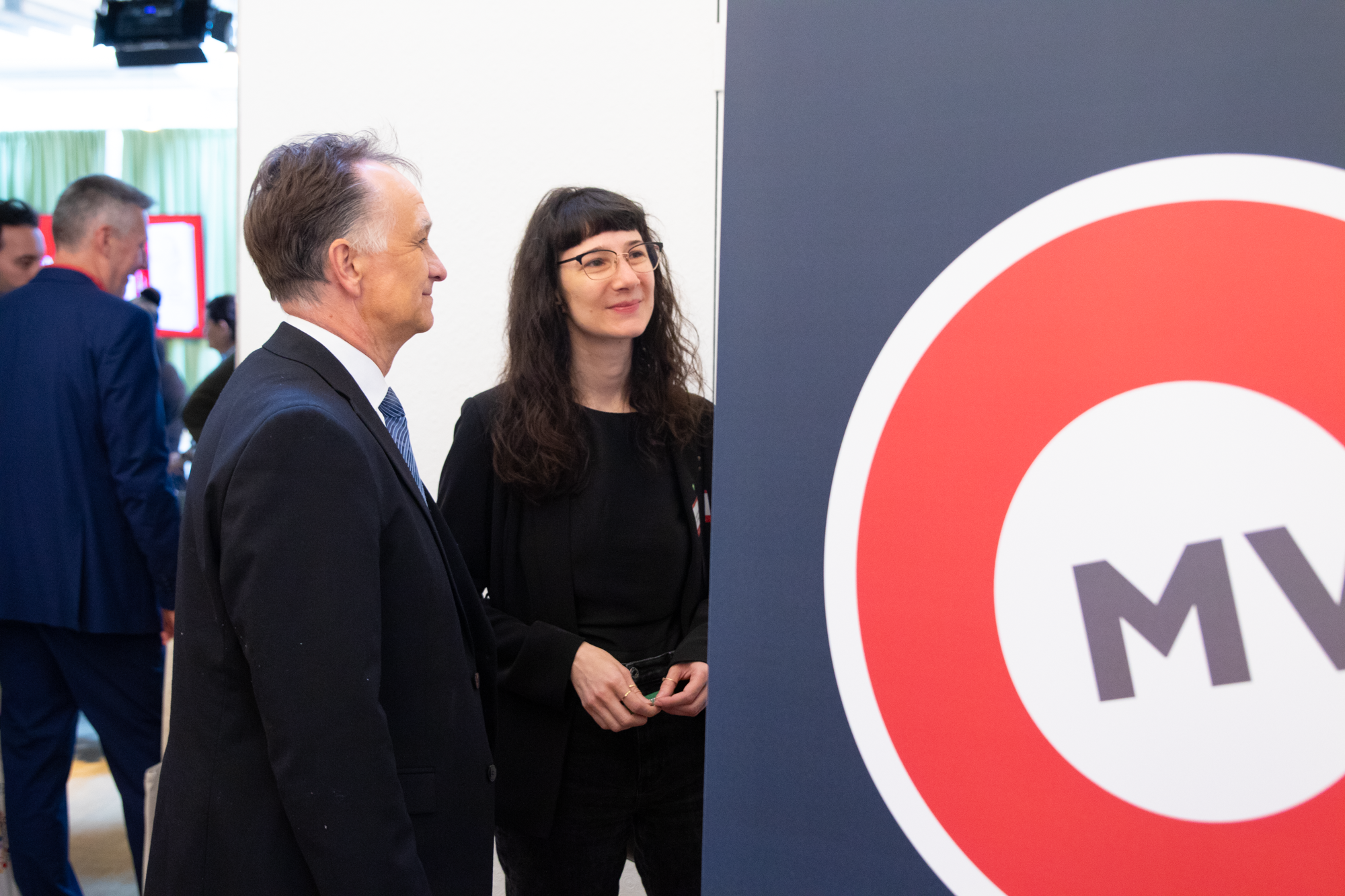 Zwei Zero Projekt Mitarbeiter unterhalten sich mit jemanden der sich hinter einem MVG Logo befindet