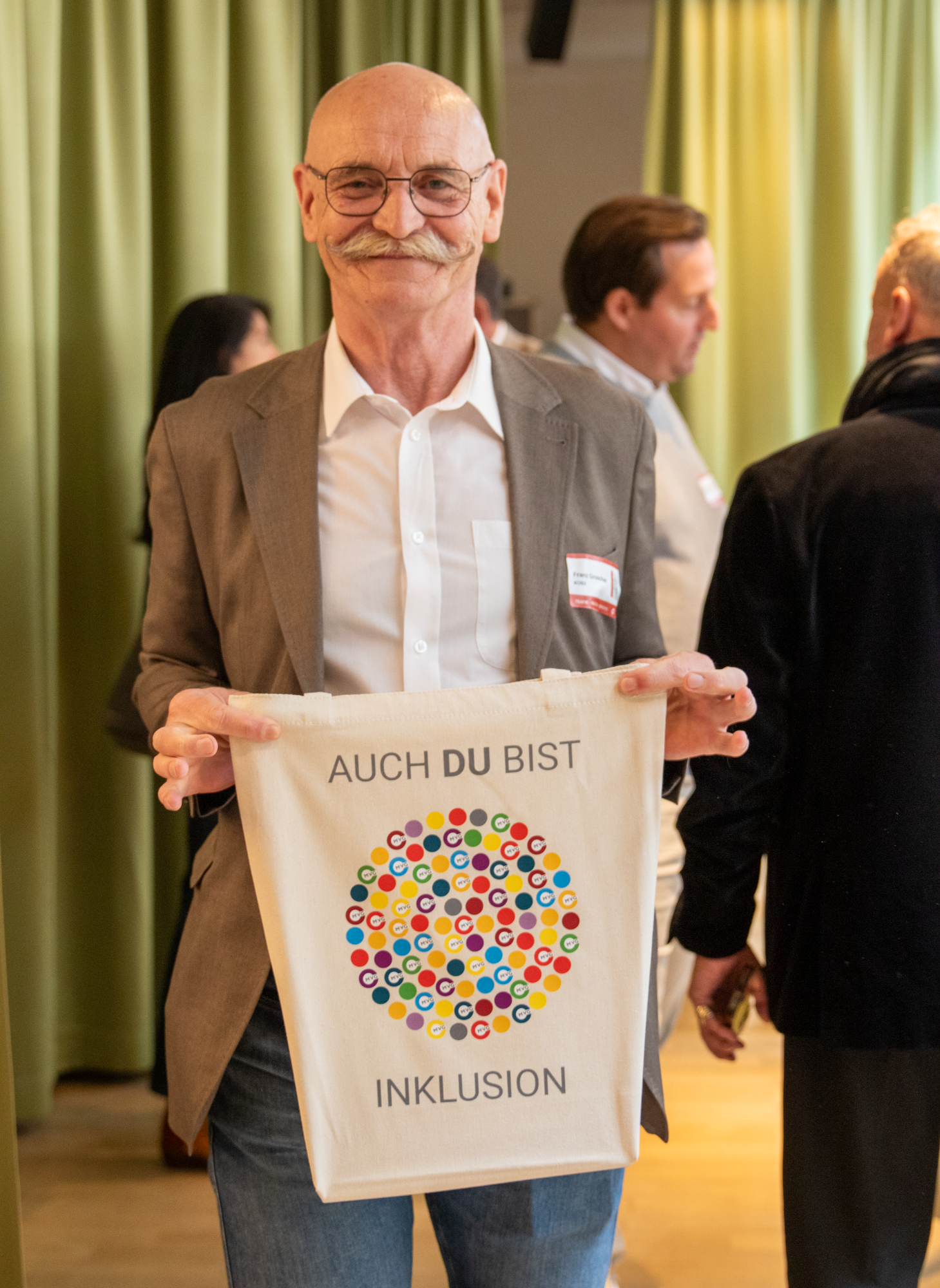 KOBV Mitarbeiter präsentiert MVG Jutebeutel mit der Aufschrift "auch du bist Inklusion"