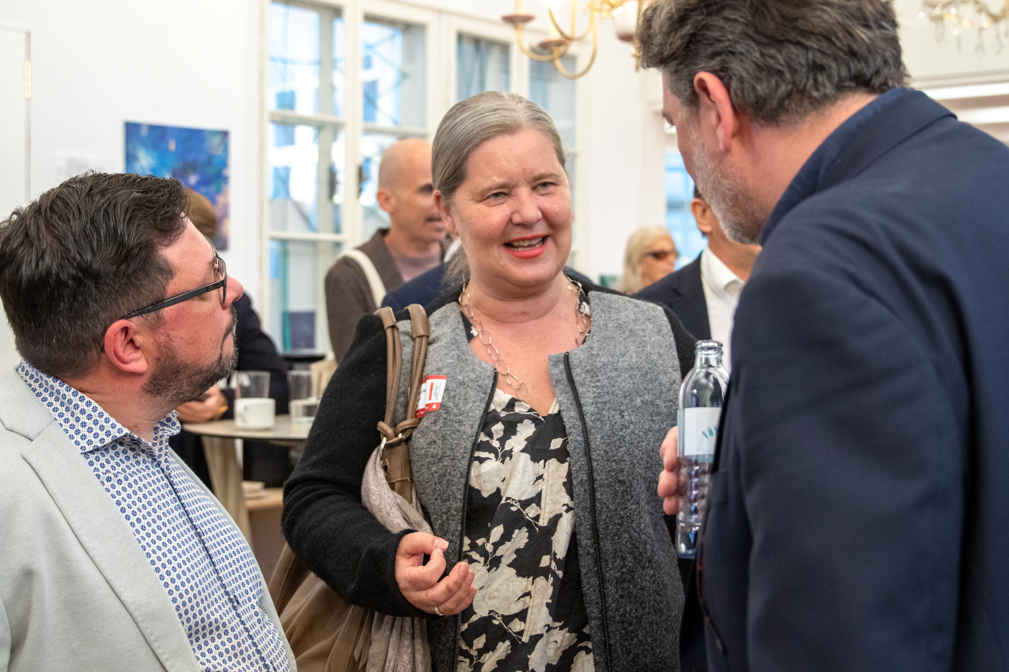 Drei Eventteilnehmer unterhalten sich, eine Frau zwischen zwei Männern