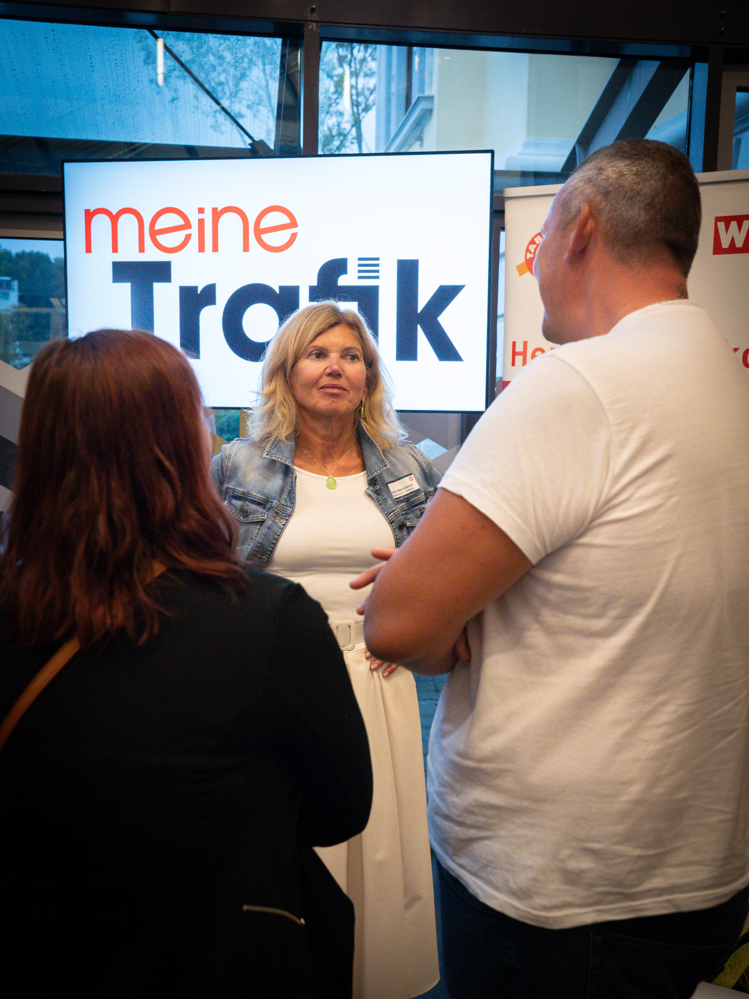 Trafikantenvertreterin unterhaltet sich mit einen Interessenten und einer Interessentin