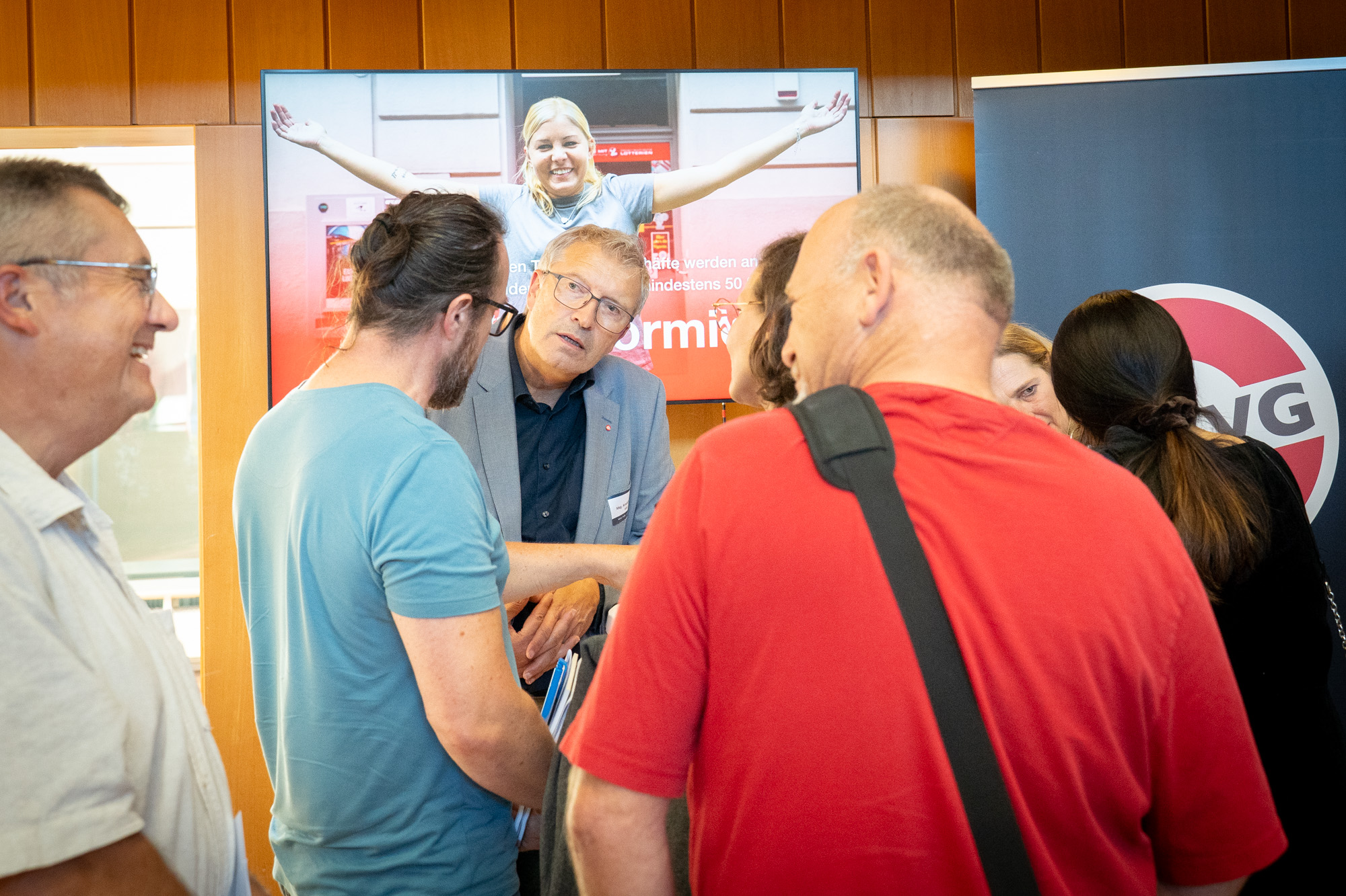 Der Monopolstellenleiter und eine Referentin stehen beim MVG Informationsstand und unterhalten sich mit mehreren Interessenten und Interessentinnen.