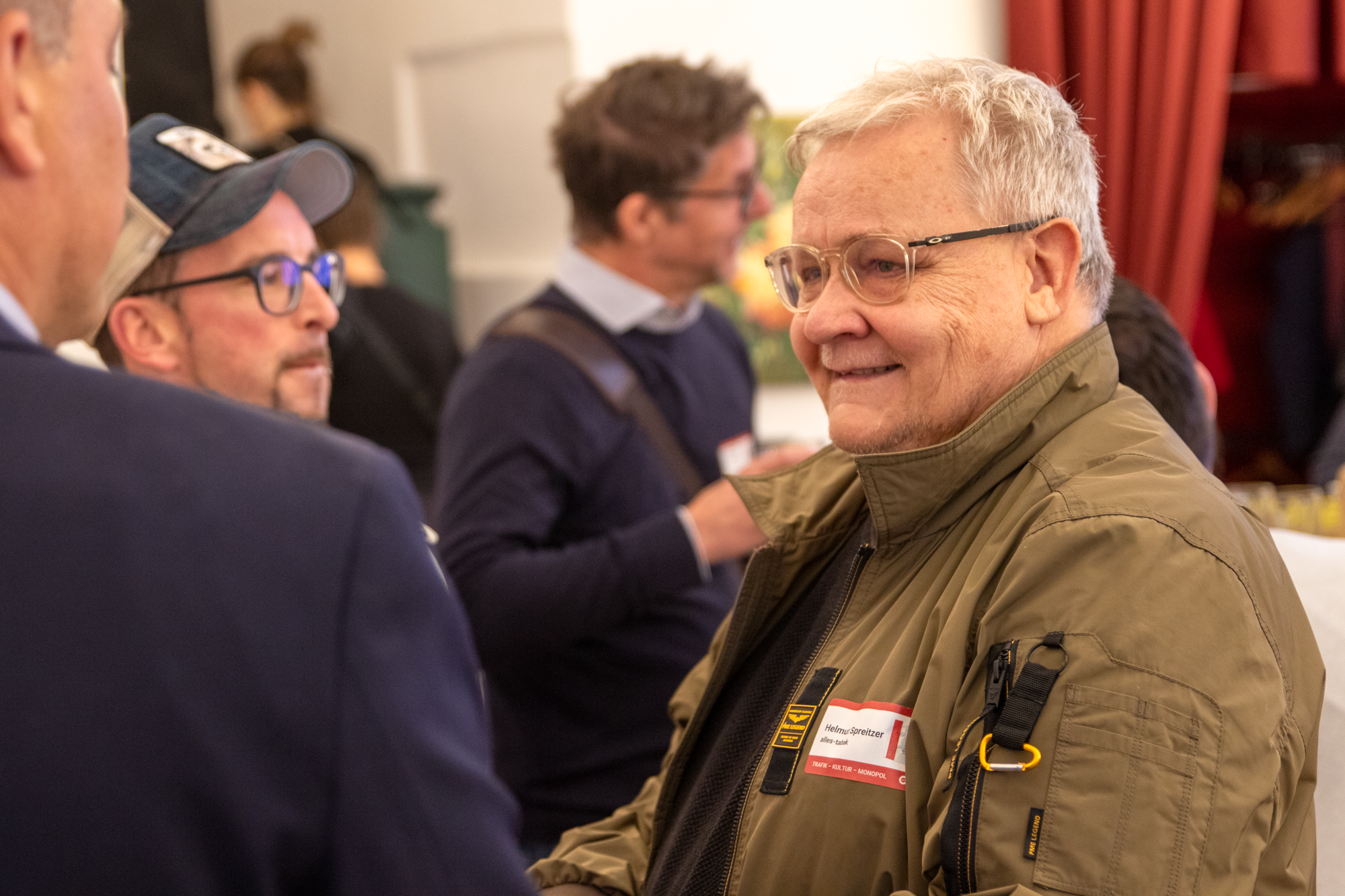 Nahaufnahme eines älteren Herren mit weißem Haar und einer grünen Jacke