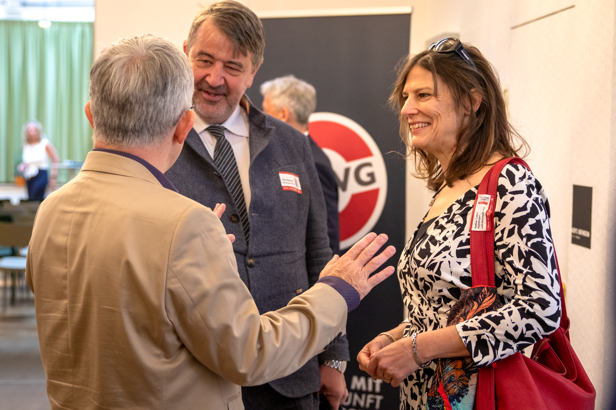 Monopolstelleleiter unterhaltet sich mit zwei Gästen, einem Mann und einer Frau