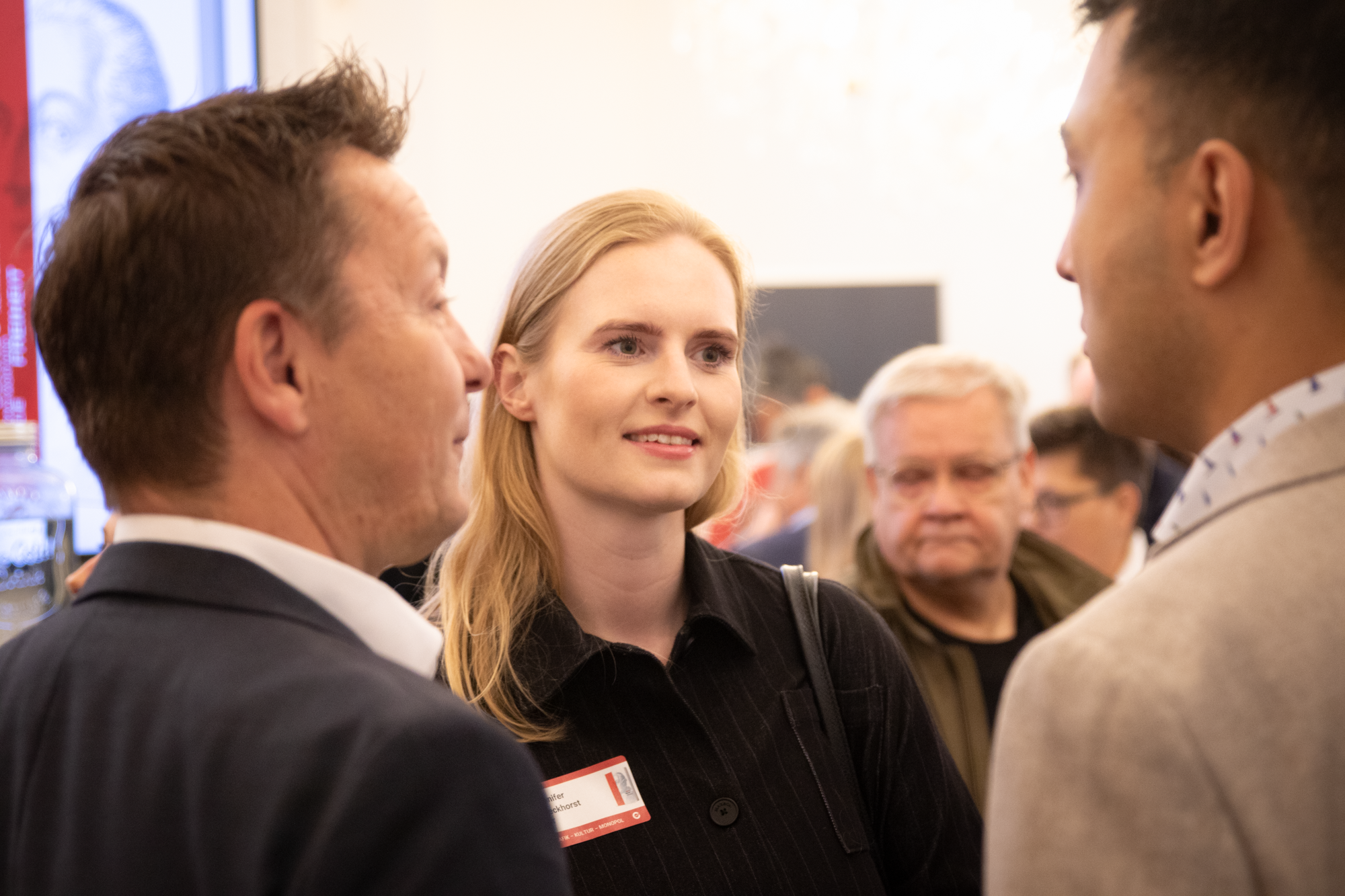 Eine blonde Frau steht zwischen zwei Männern