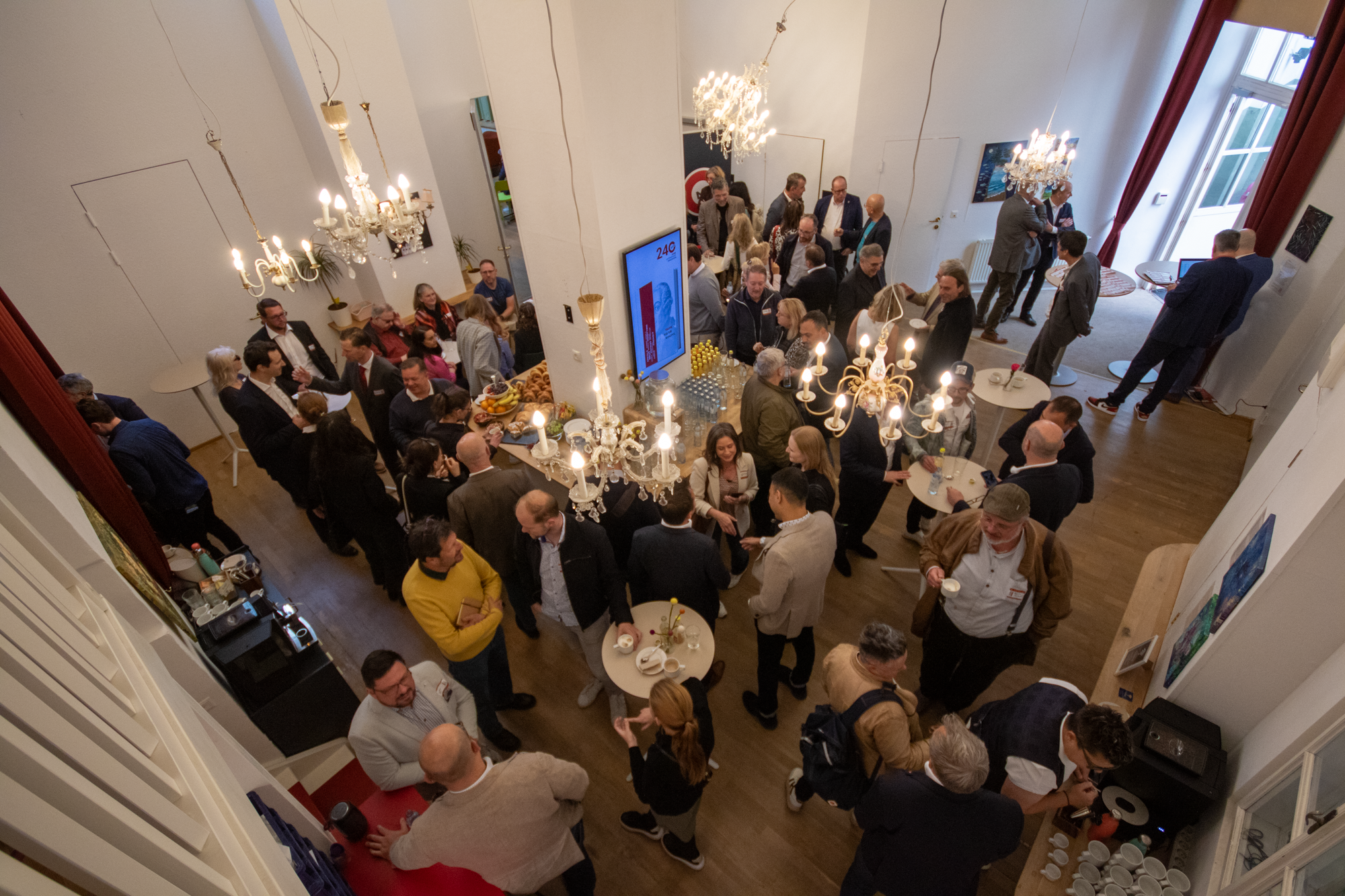Perspektive von oben, eine Gruppe von Besuchern versammeln sich in einem Raum und warten bis die Veranstaltung anfängt