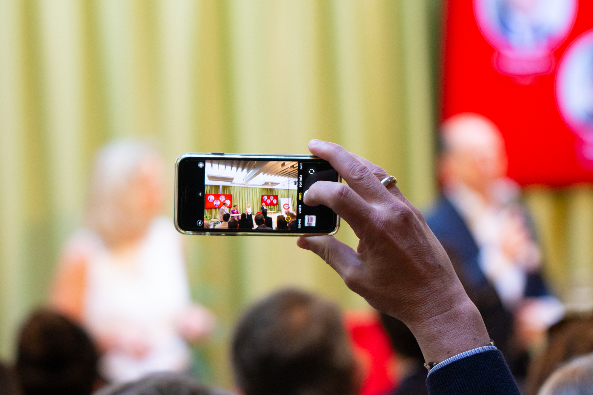 Ein Mann fotografiert mit einem Handy die Bühne 