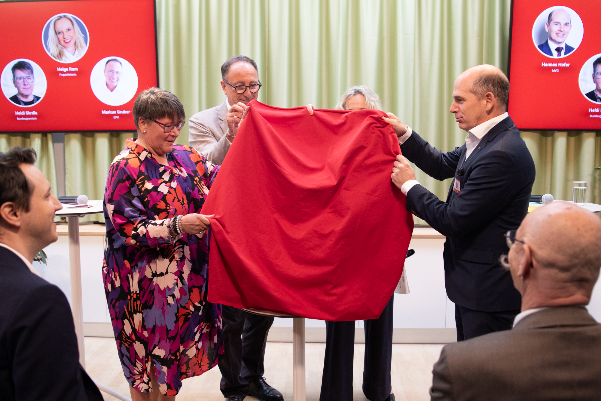 Vier Personen stehen auf der Bühne, in Ihrer Hand befindet sich ein rotes Tuch