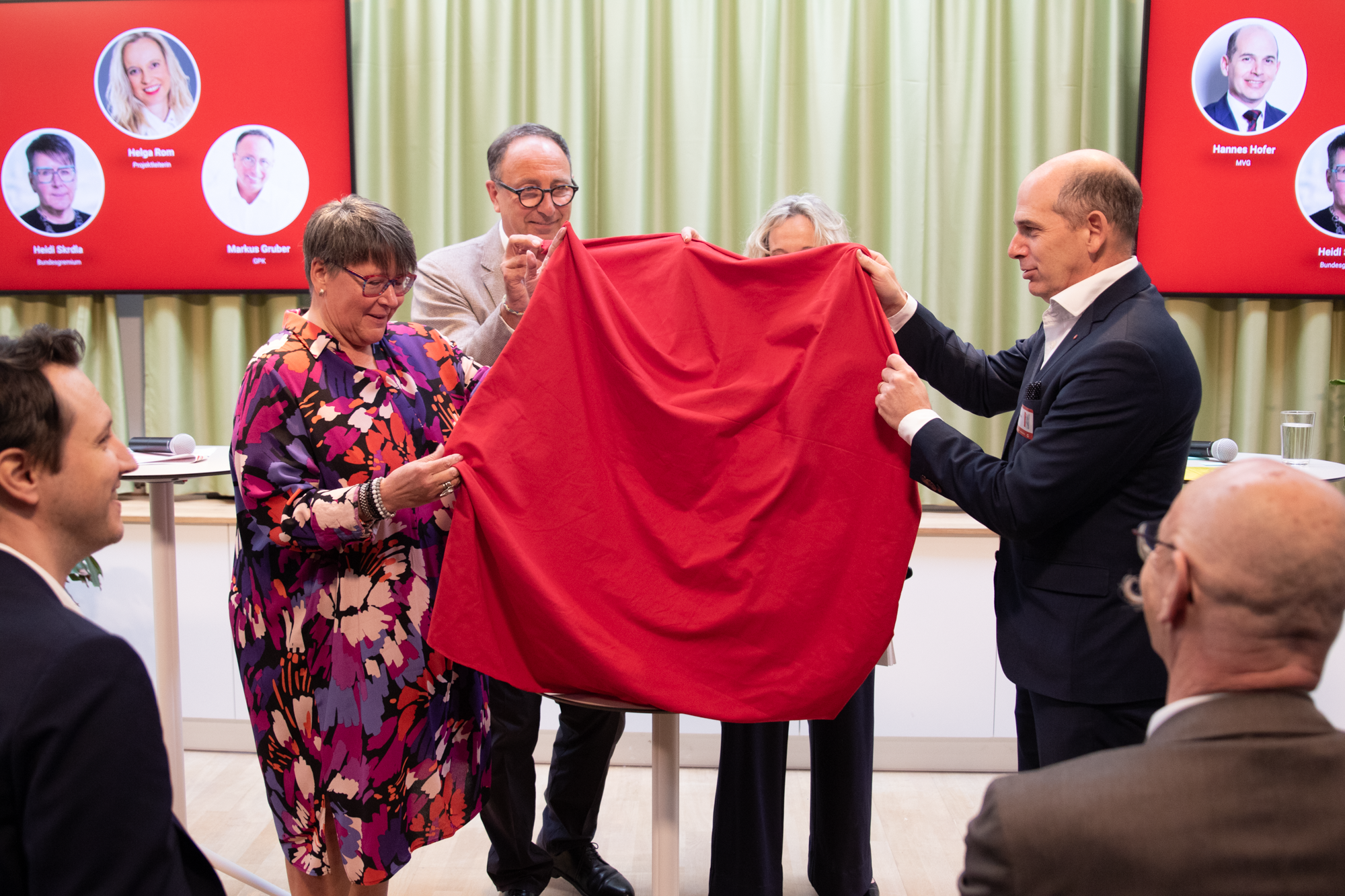 Vier Personen stehen auf der Bühne, in Ihrer Hand befindet sich ein rotes Tuch