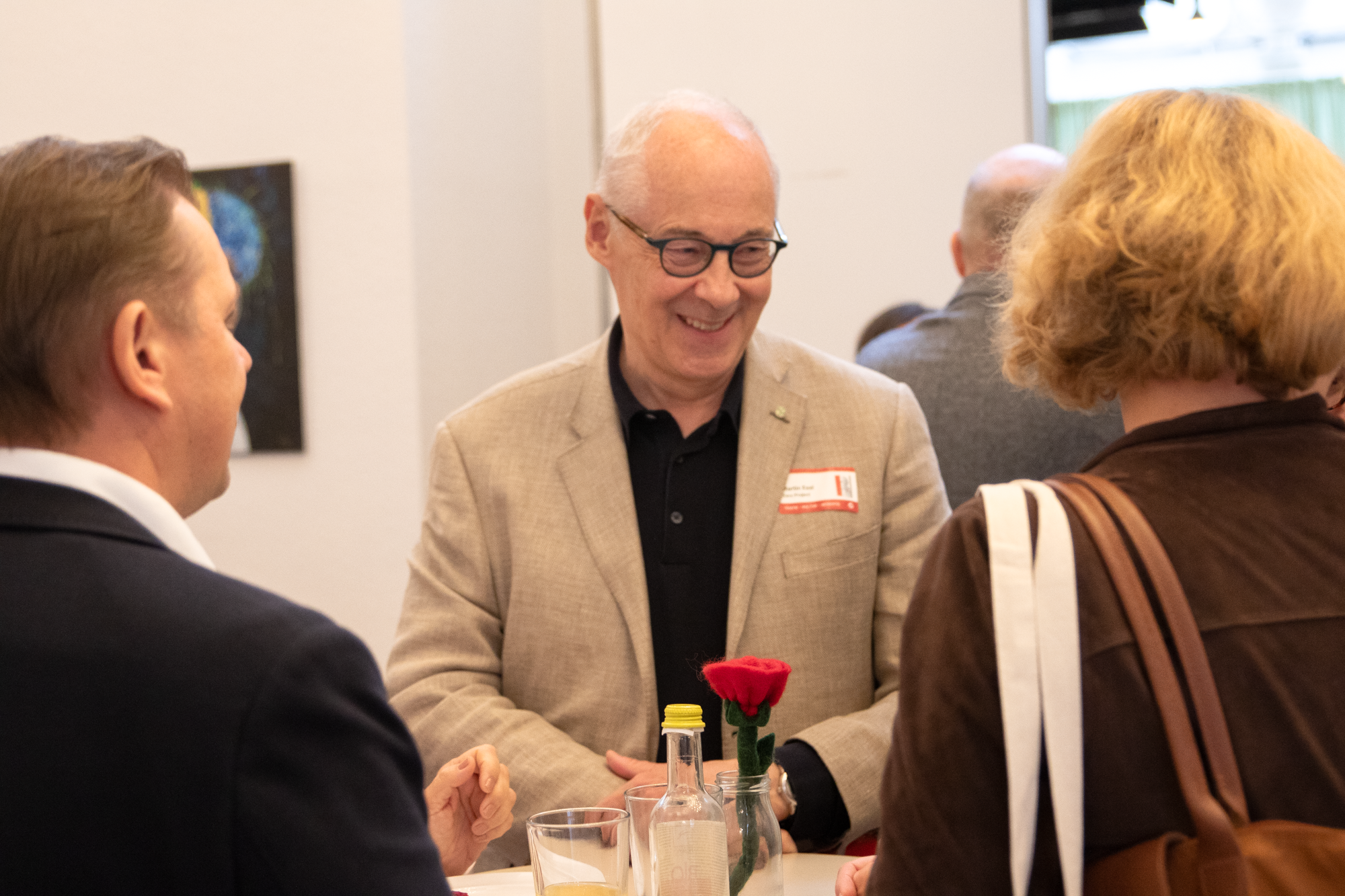 Drei Teilnehmer der Buchveranstaltung sind bei einem runden Tisch versammelt und unterhalten sich