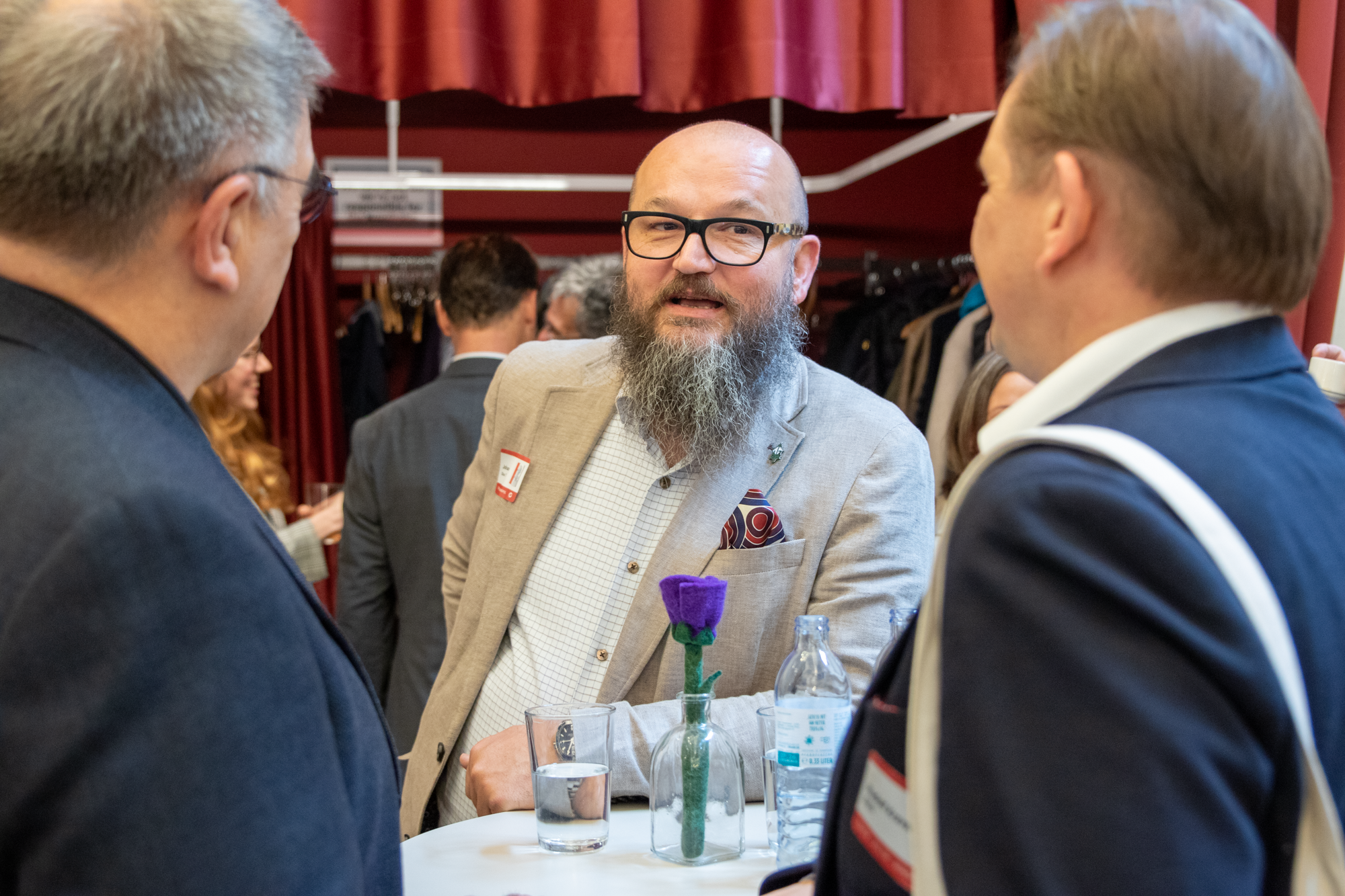 Drei Männer stehen um einen runden Tisch und unterhalten sich