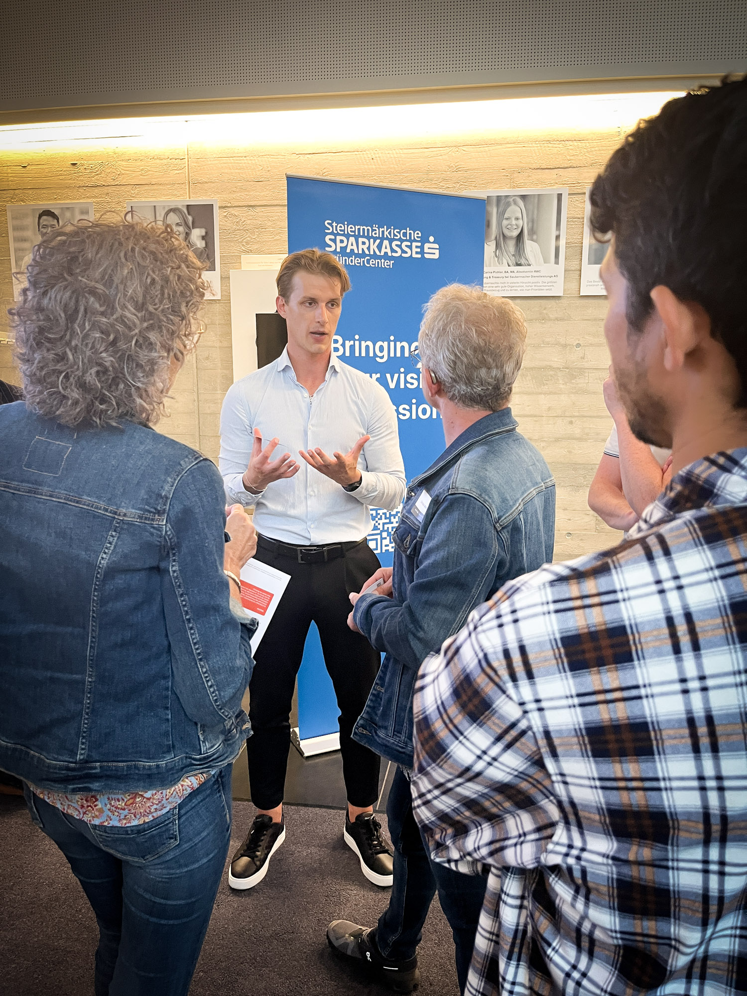 Sparkassenmitarbeiter unterhält sich mit einer Gruppe Interessenten