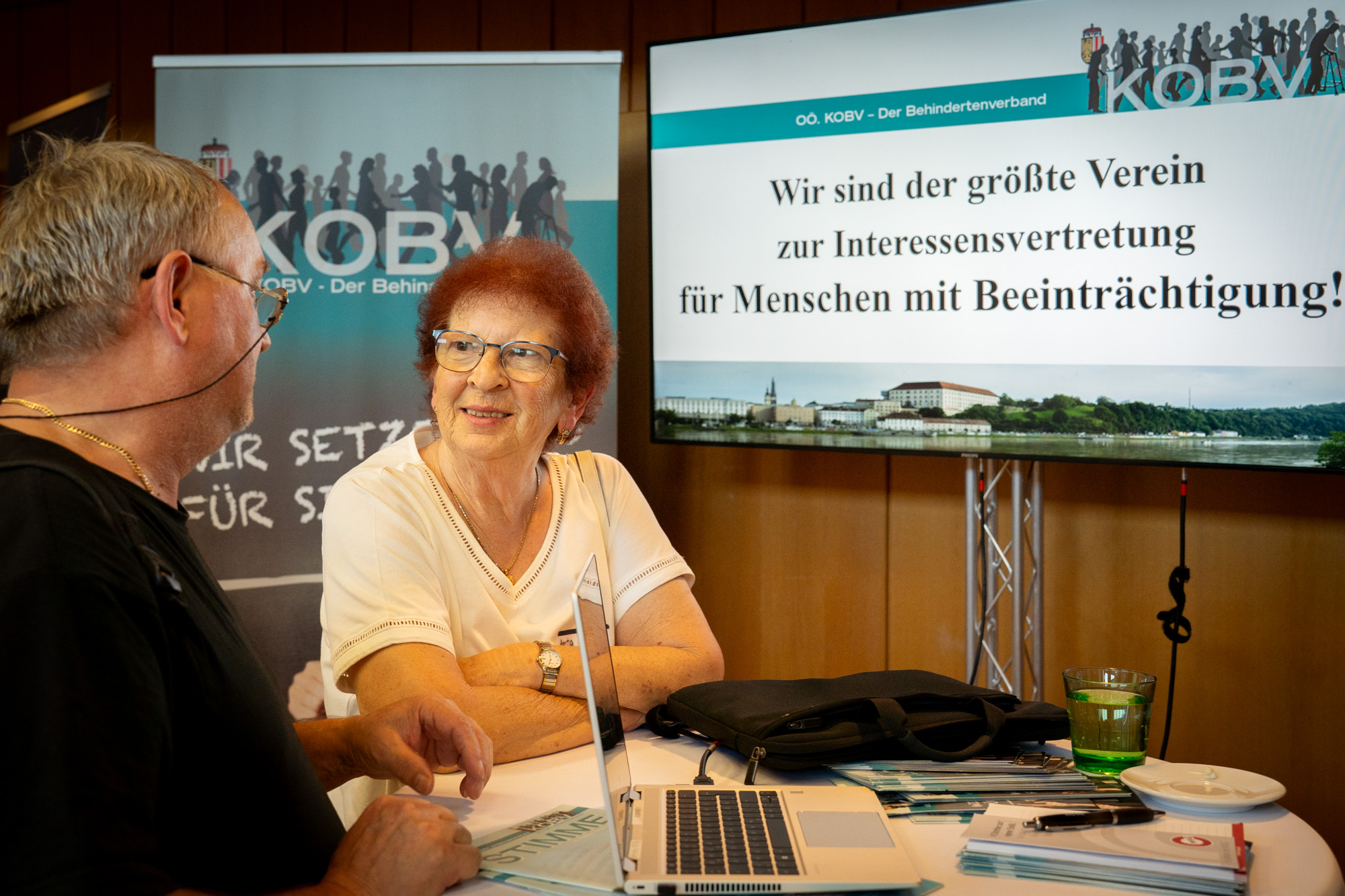 Eine KOBV Mitarbeiterin erzählt einem Interessenten etwas über ihre Organisation