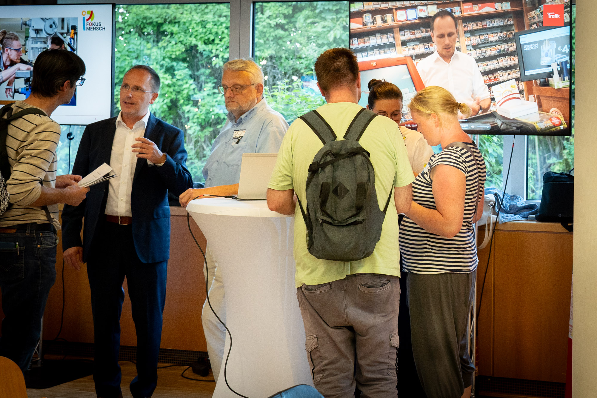 Ein Infostand von meiner Trafik ist im Bild zusehen. Dabei umkreisen ihn verschiedene Interessenten und Interessentinnen, die Infomaterial in der Hand haben. 